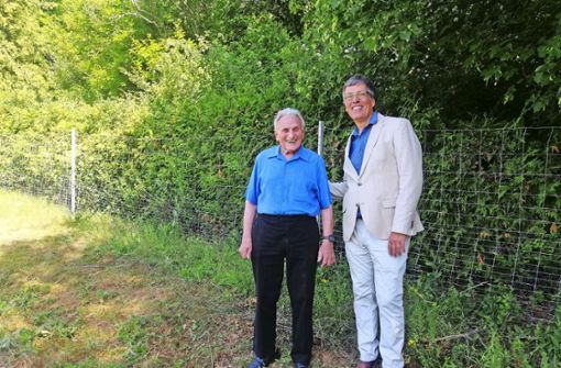 Helmut Mechtold und Pfarrer Michael Herzer präsentieren den neuen Zaun am Seidmannsdorfer Friedhof. Foto: /Schäfer