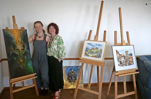 Artothek-Leiterin Elke Bauer (rechts) und die Malerin Andrea Krause präsentieren einige der  ausleihbaren Werke, die vorerst im evangelischen Gemeindehaus zu sehen sind. Foto: Dieter Ungelenk