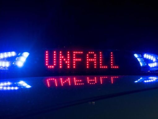 Das Blaulicht auf einem Fahrzeug der Polizei leuchtet in der Dunkelheit, auf dem Display ist der Hinweis «Unfall» zu lesen. Foto: Monika Skolimowska/Archiv